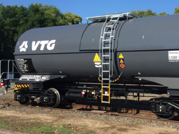 Dark grey mineral oil tank wagon with ladder under a blue sky