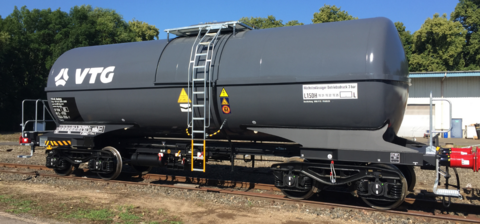 Dark grey mineral oil tank wagon with ladder under a blue sky