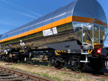 Silver liquefied gas tank car with orange stripe under a blue sky