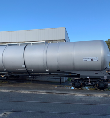 Gray tank car with lettering in front of hall