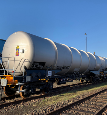 Gray tank car on track under a blue sky