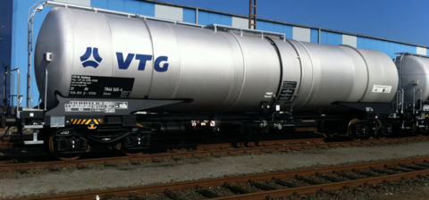 Silver tank wagon on rails in front of blue hall