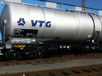 Silver tank wagon on rails in front of blue hall